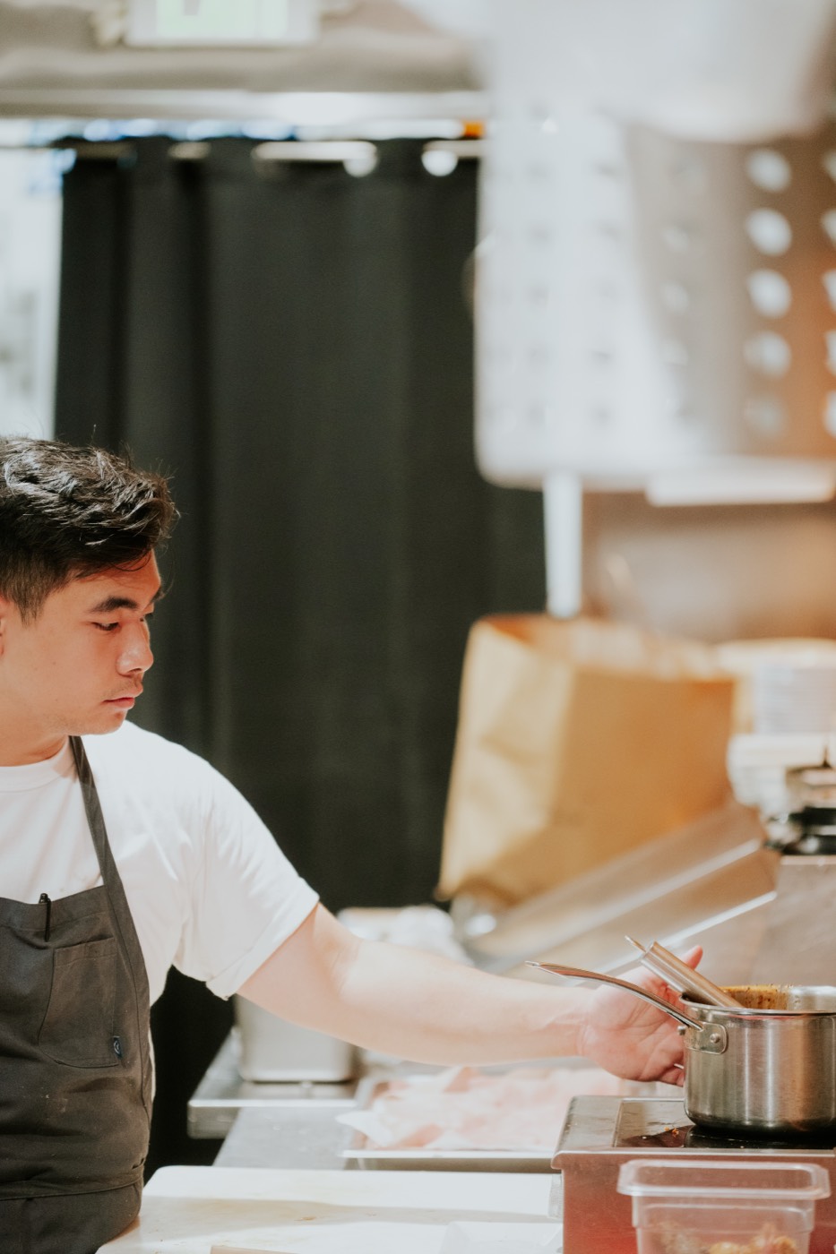 A cook stirring a pot at the stove