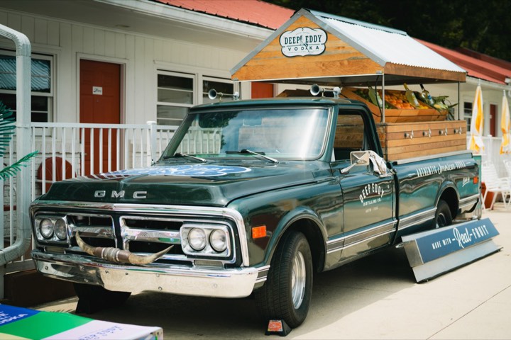 A vintage green GMC pickup fitted out as a Deep Eddy Vodka bar, parked outside the venue